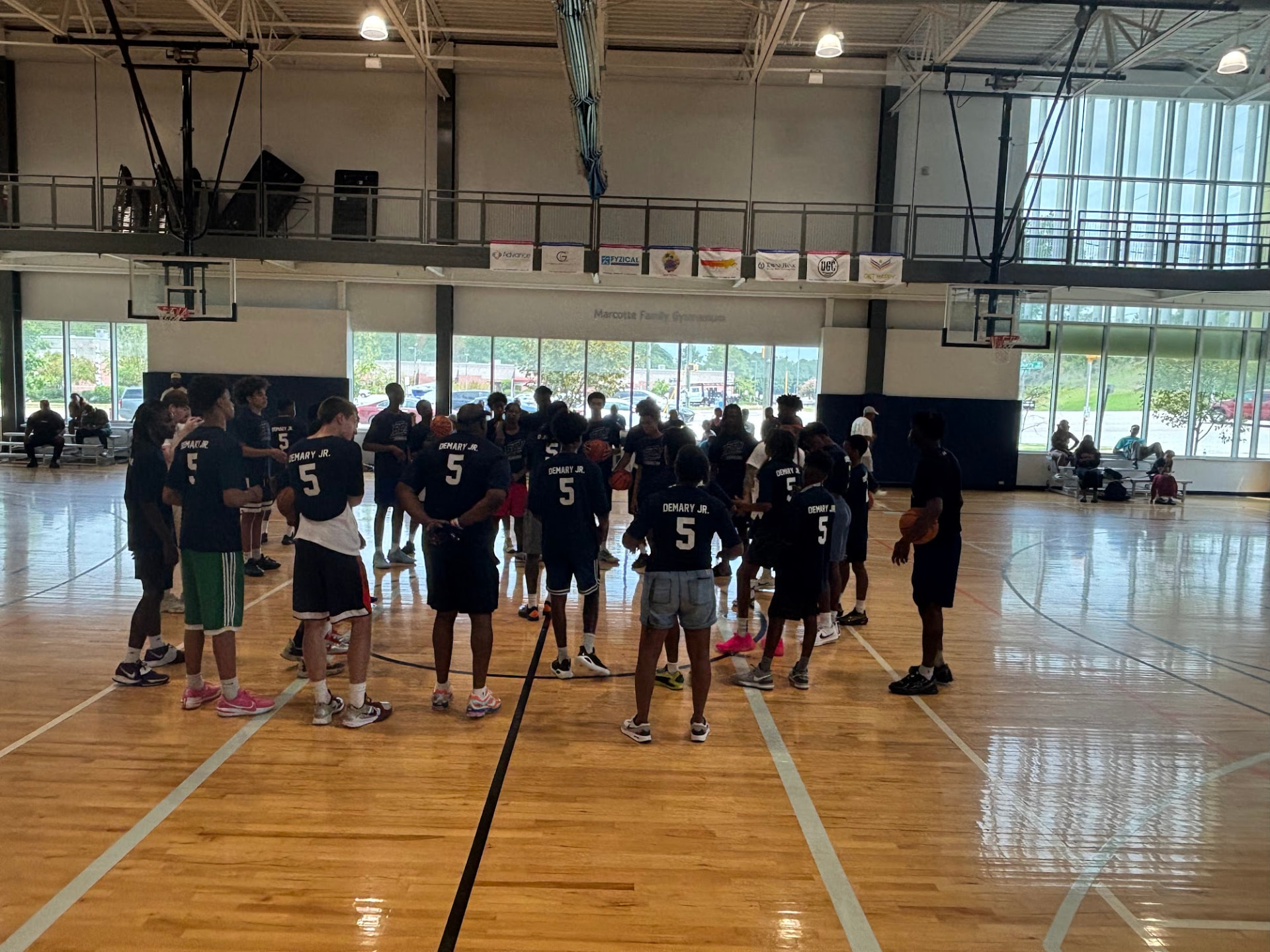 A group of young athletes wearing Demary Jr. jerseys gather on the court at the Raleigh camp.