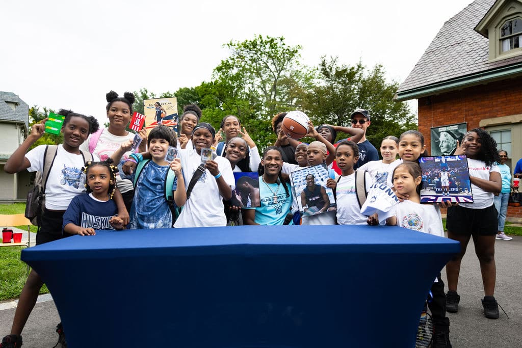 Kids showing off backpacks, posters, and a signed basketball