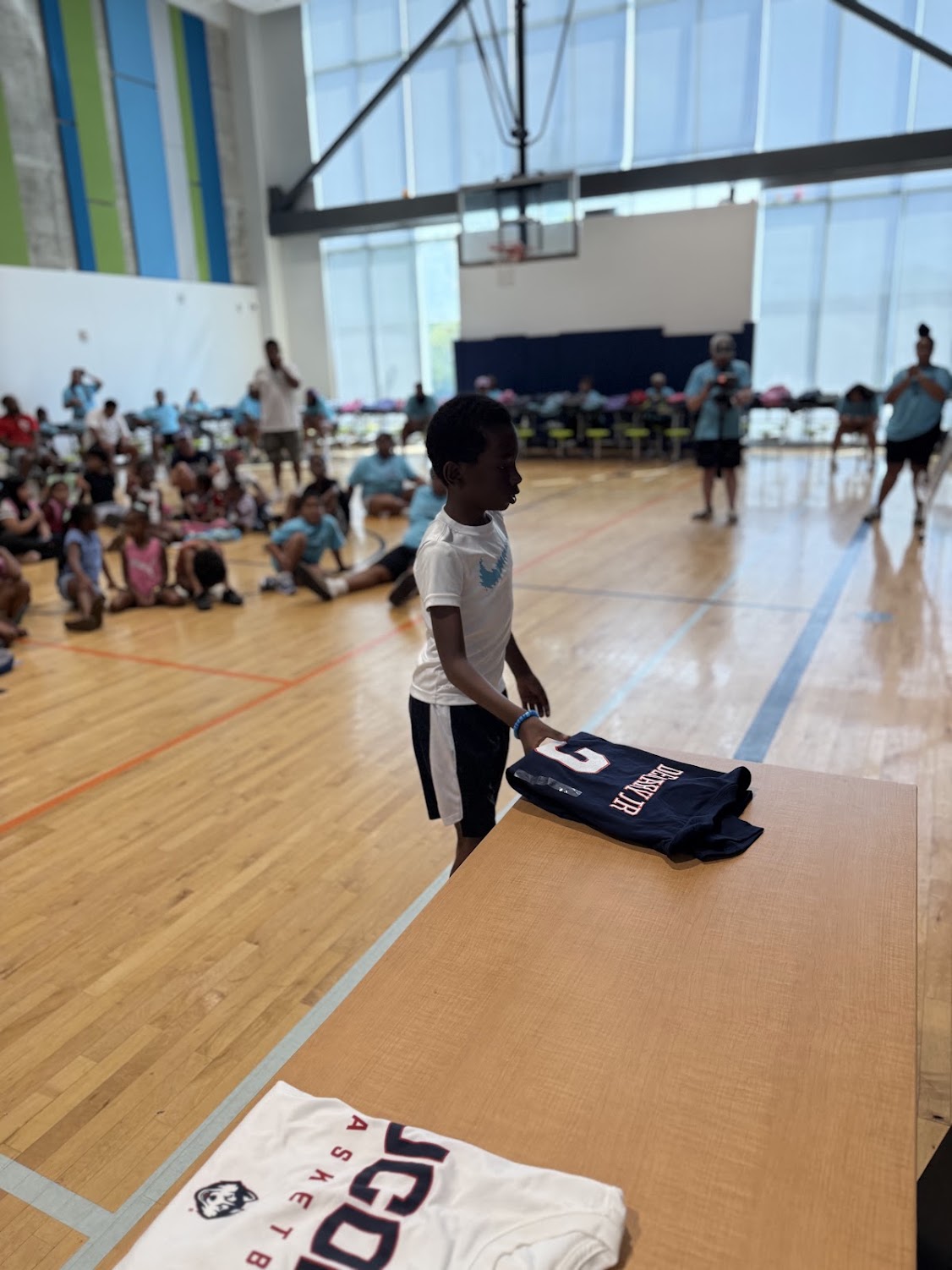 A young boy reaches for a folded UConn jersey on the gym floor at the Raleigh bash.