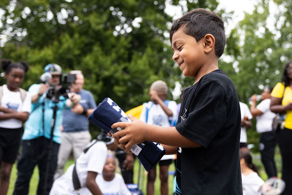 A young boy laughing while holding a giveaway t-shirt