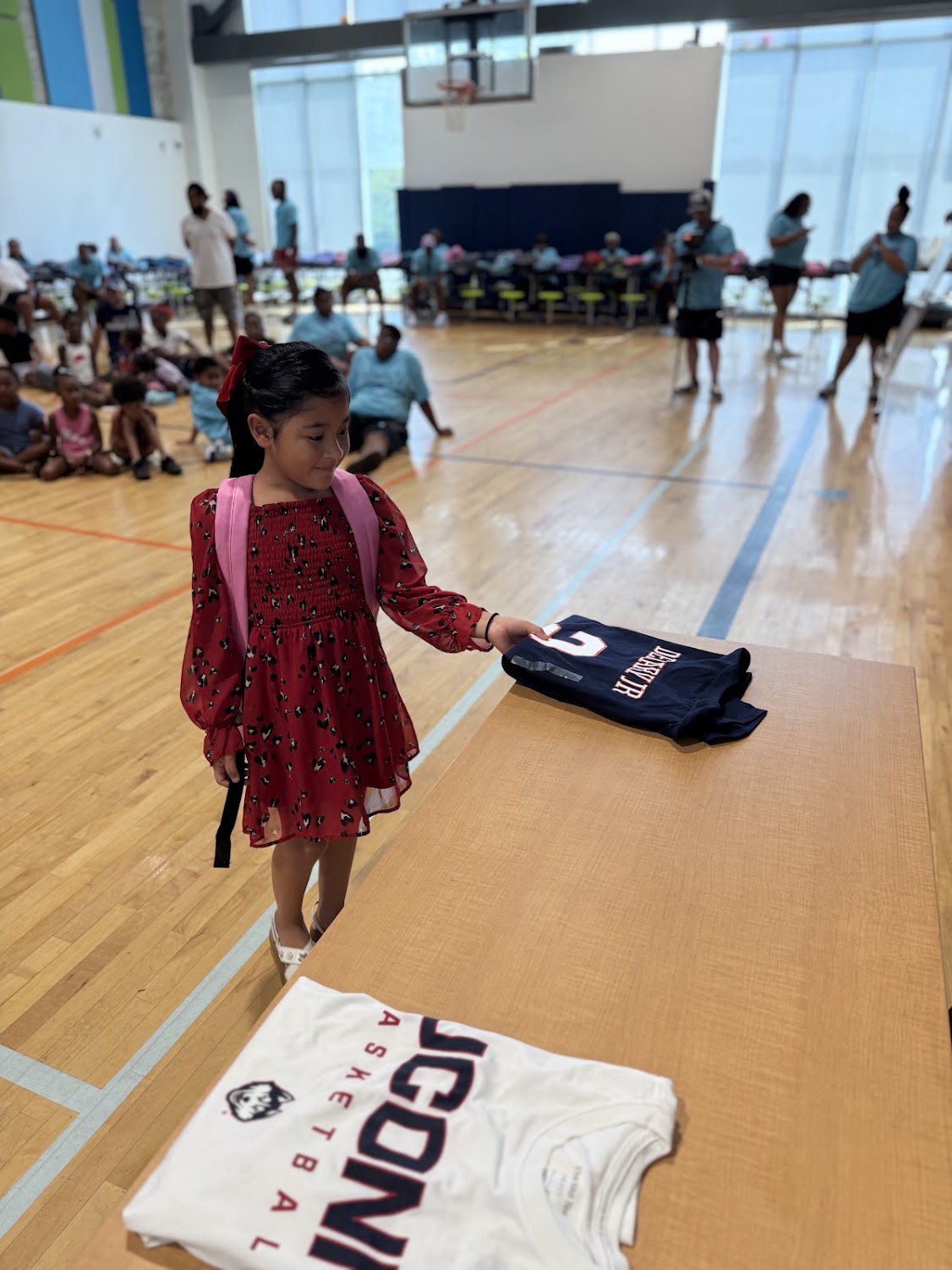 A young girl in a red dress reaches for a UConn jersey at the Raleigh bash.