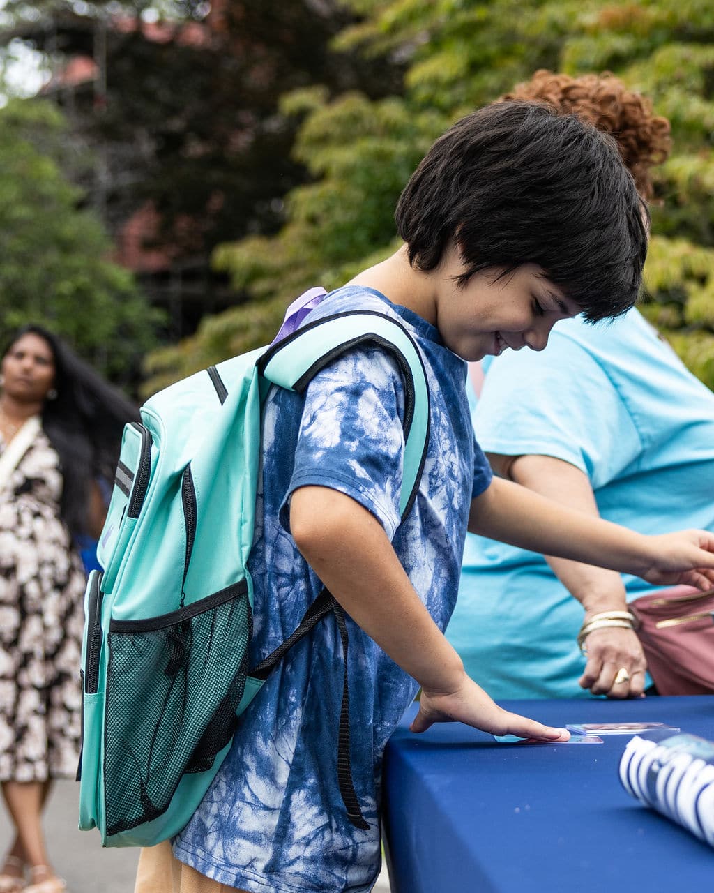 A boy with a new backpack picking up a signed photo