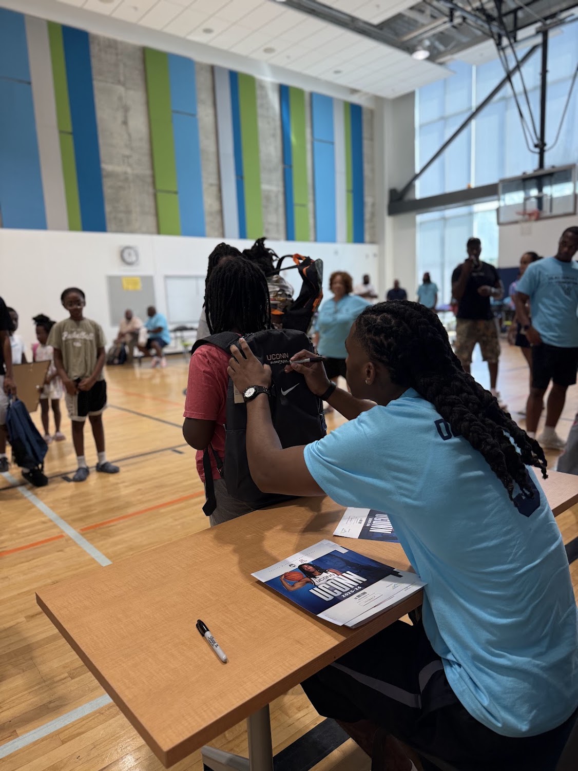 Silas Demary Jr. signs a UConn backpack for a young participant at the 2026 Raleigh Back to School Bash.