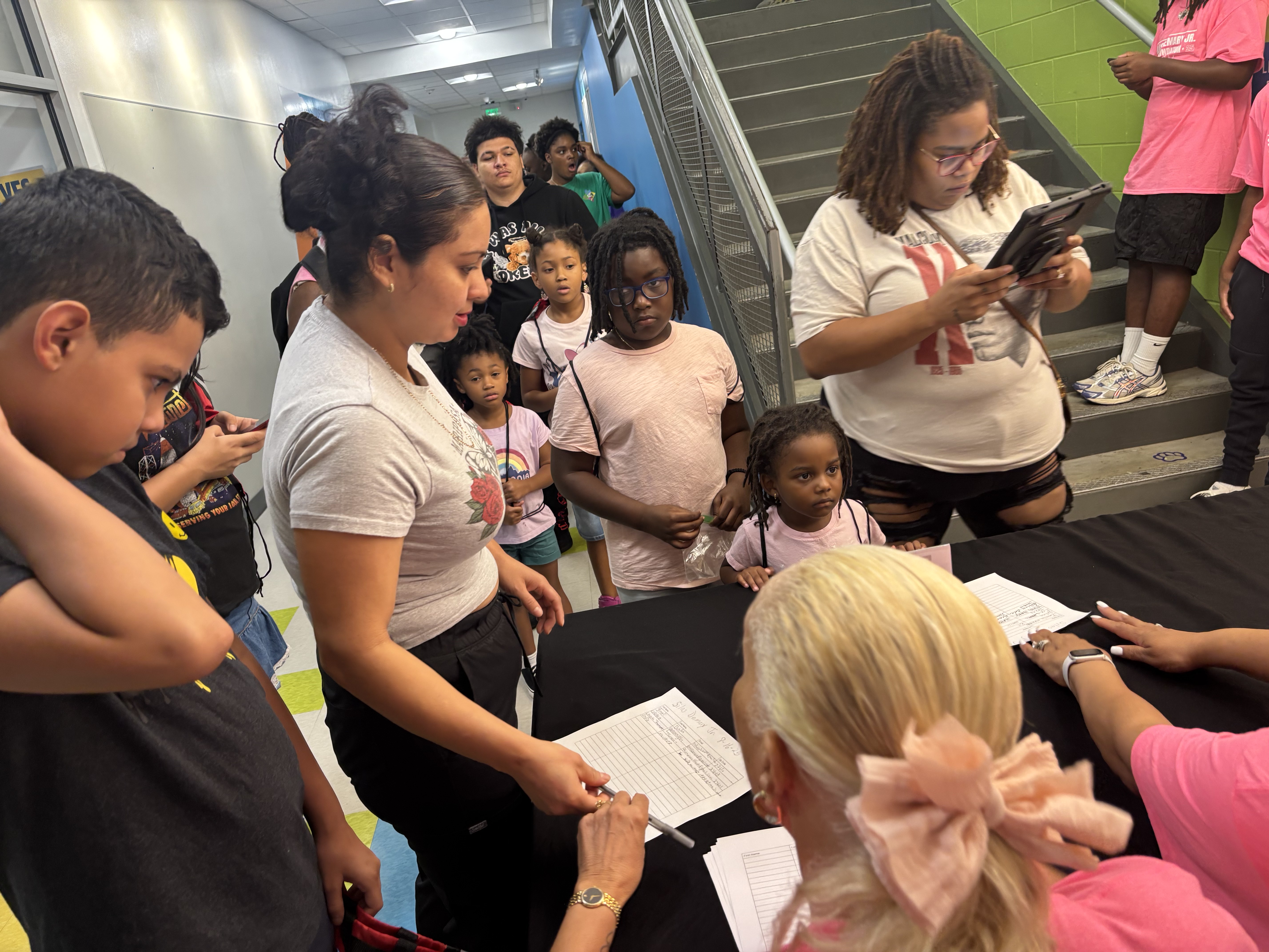 Families check in at the registration table while kids line up at the 2025 Back to School Bash.