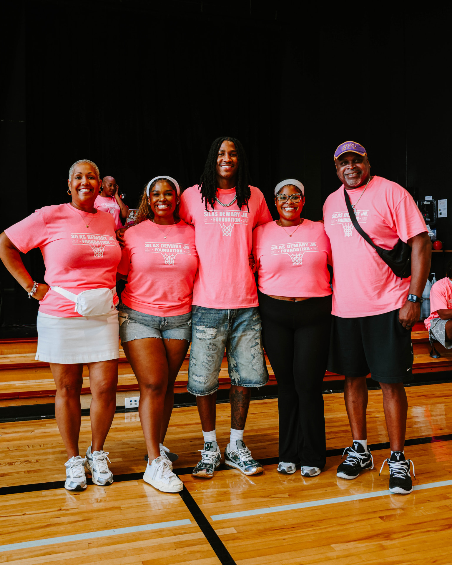 Family members and volunteers pose together in matching foundation shirts at the 2025 Back to School Bash.