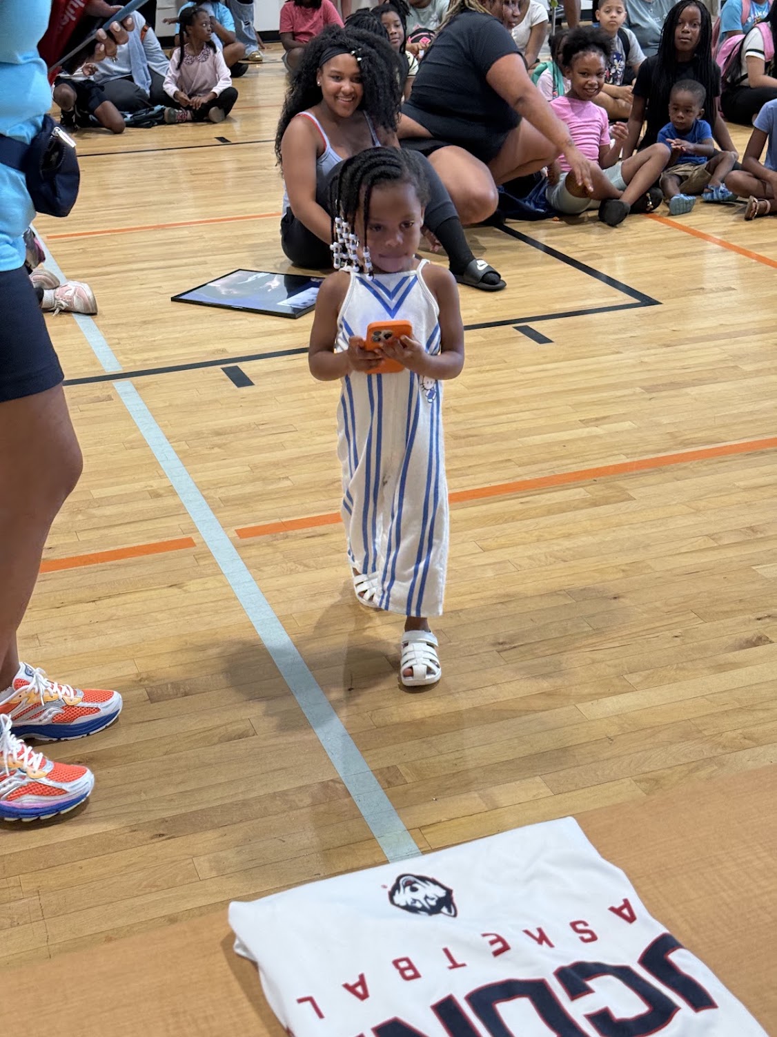 A young girl takes part in an activity while families watch from the gym floor at the Raleigh bash.