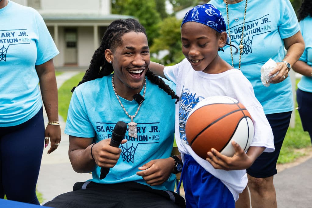 Silas Demary Jr. with a microphone and a young fan at the bash