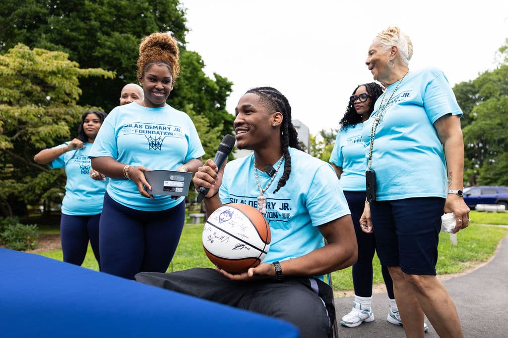 Silas Demary Jr. holding a signed basketball with foundation volunteers