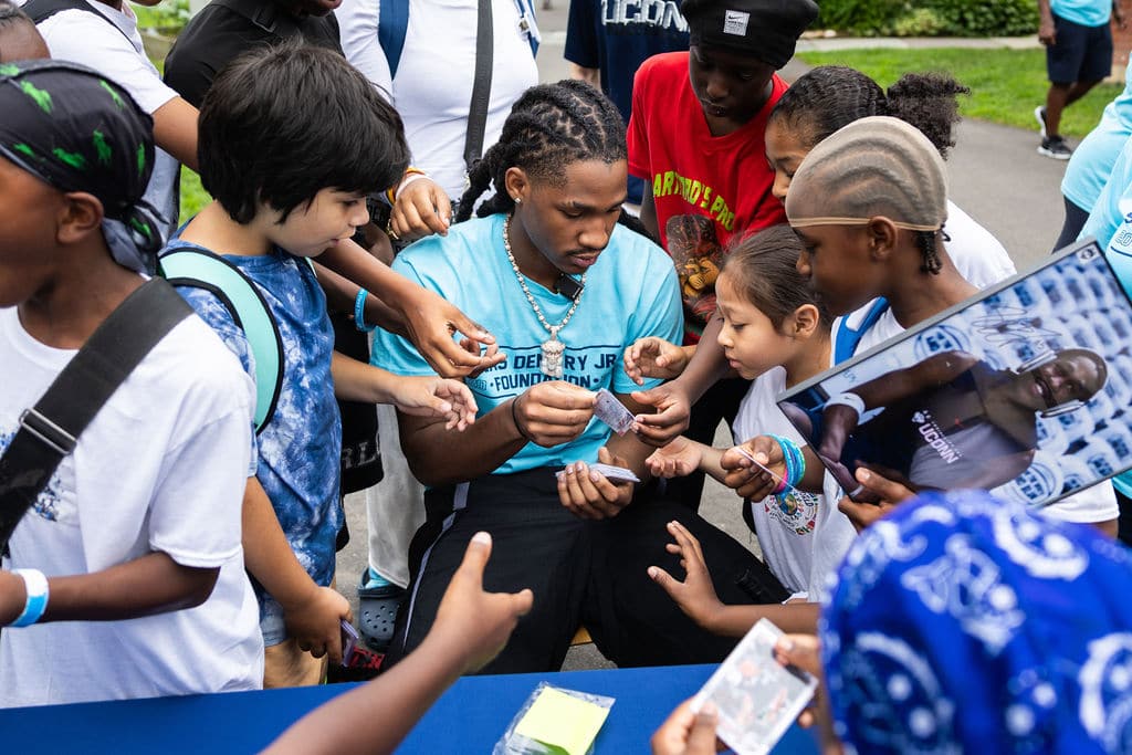 Silas Demary Jr. passing autographs to a crowd of young fans