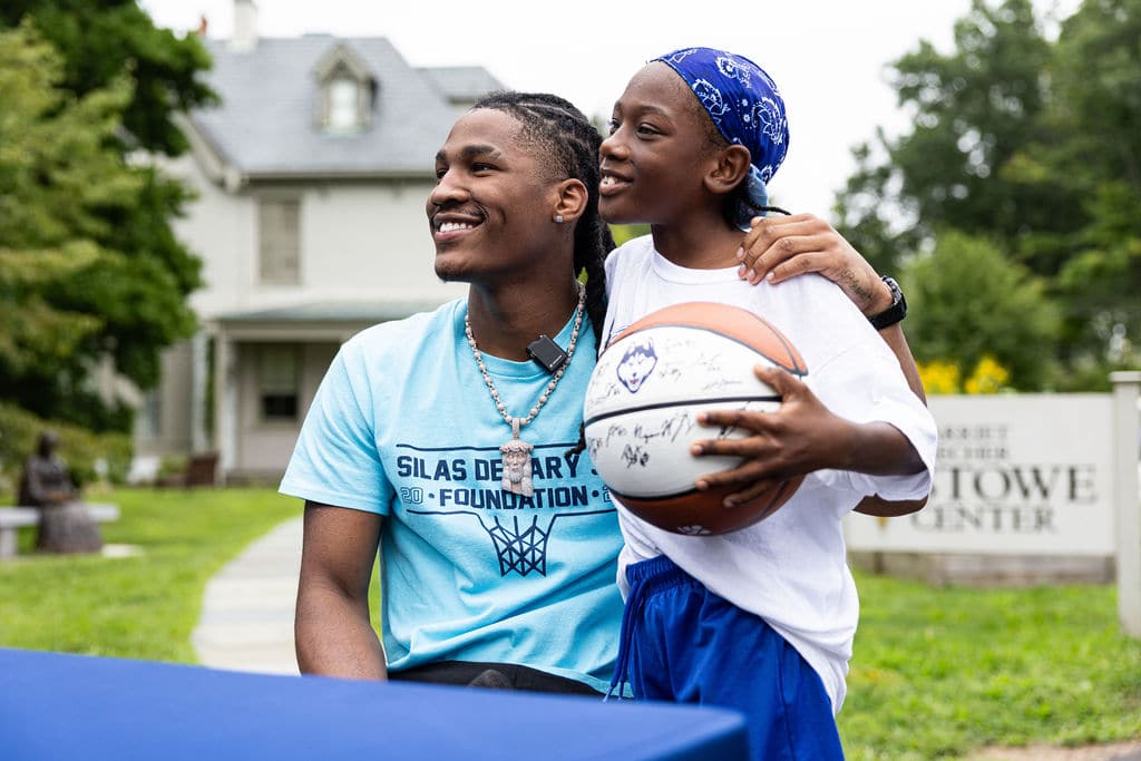 Silas Demary Jr. laughing with a young fan holding a signed basketball