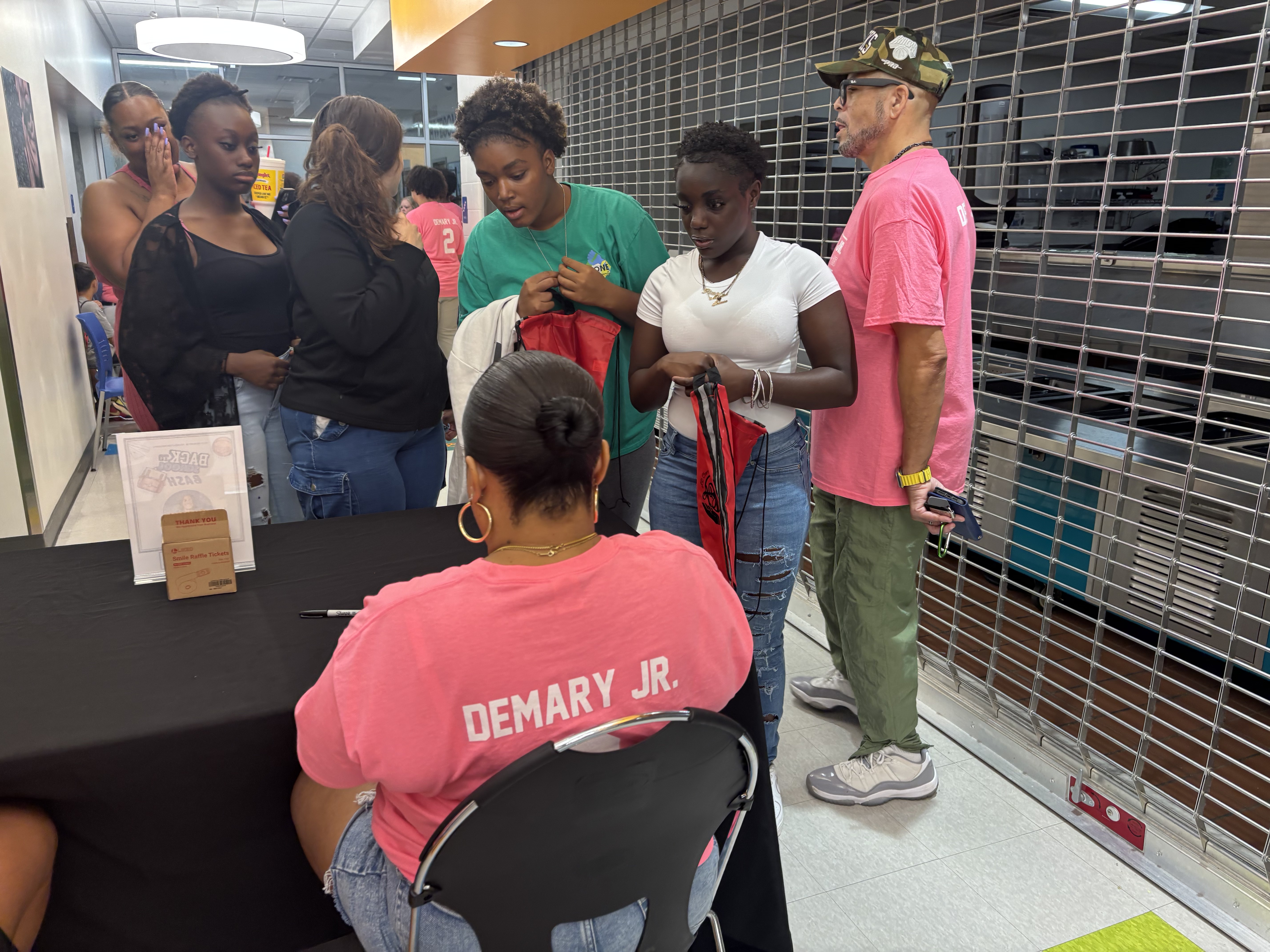 Attendees pick up drawstring backpacks from volunteers at the giveaway table at the 2025 Back to School Bash.