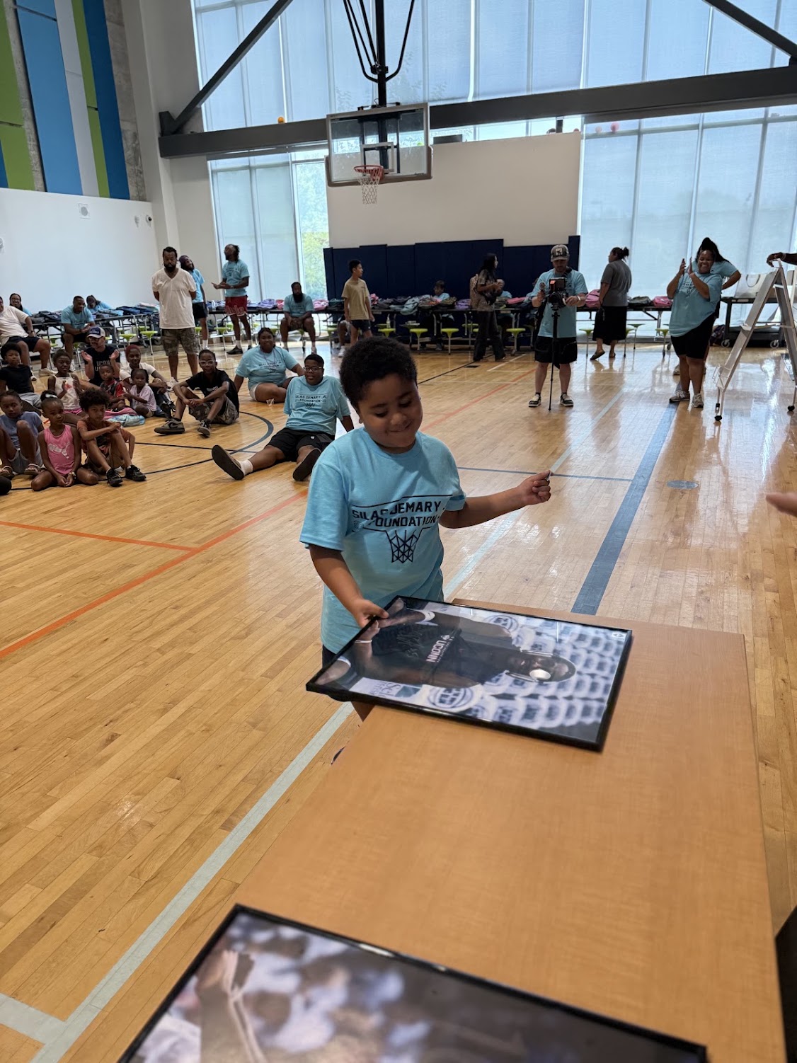 A child lifts a framed Silas Demary Jr. photo during the 2026 Raleigh Back to School Bash.