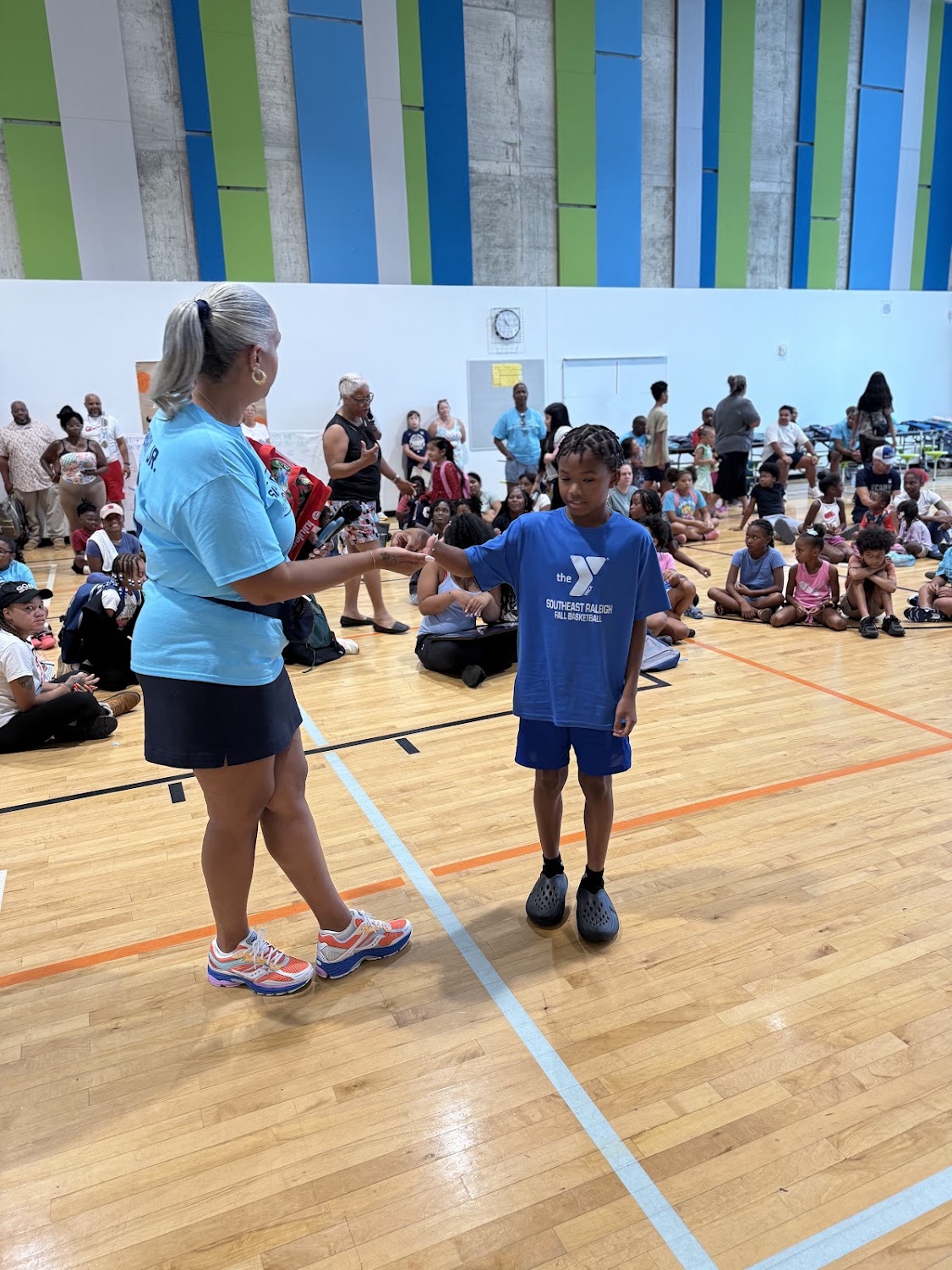 Shanté Demary shakes hands with a young boy in a Southeast Raleigh Fall Basketball shirt.