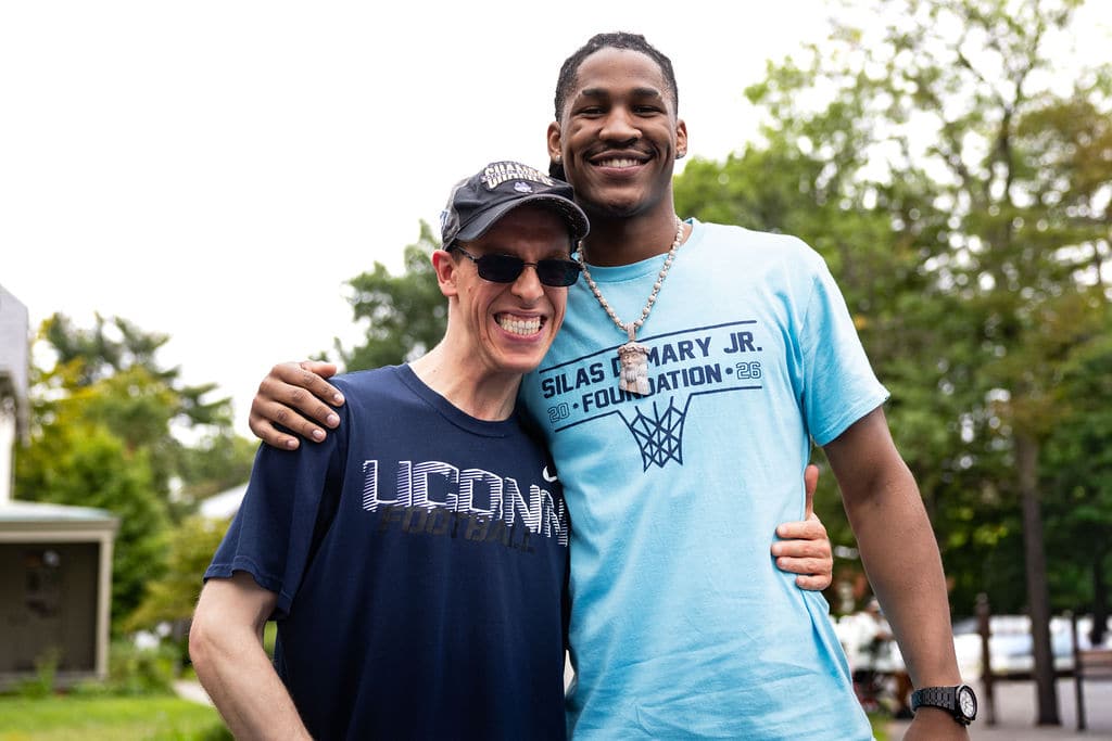 Silas Demary Jr. posing with a supporter in a UConn Football shirt