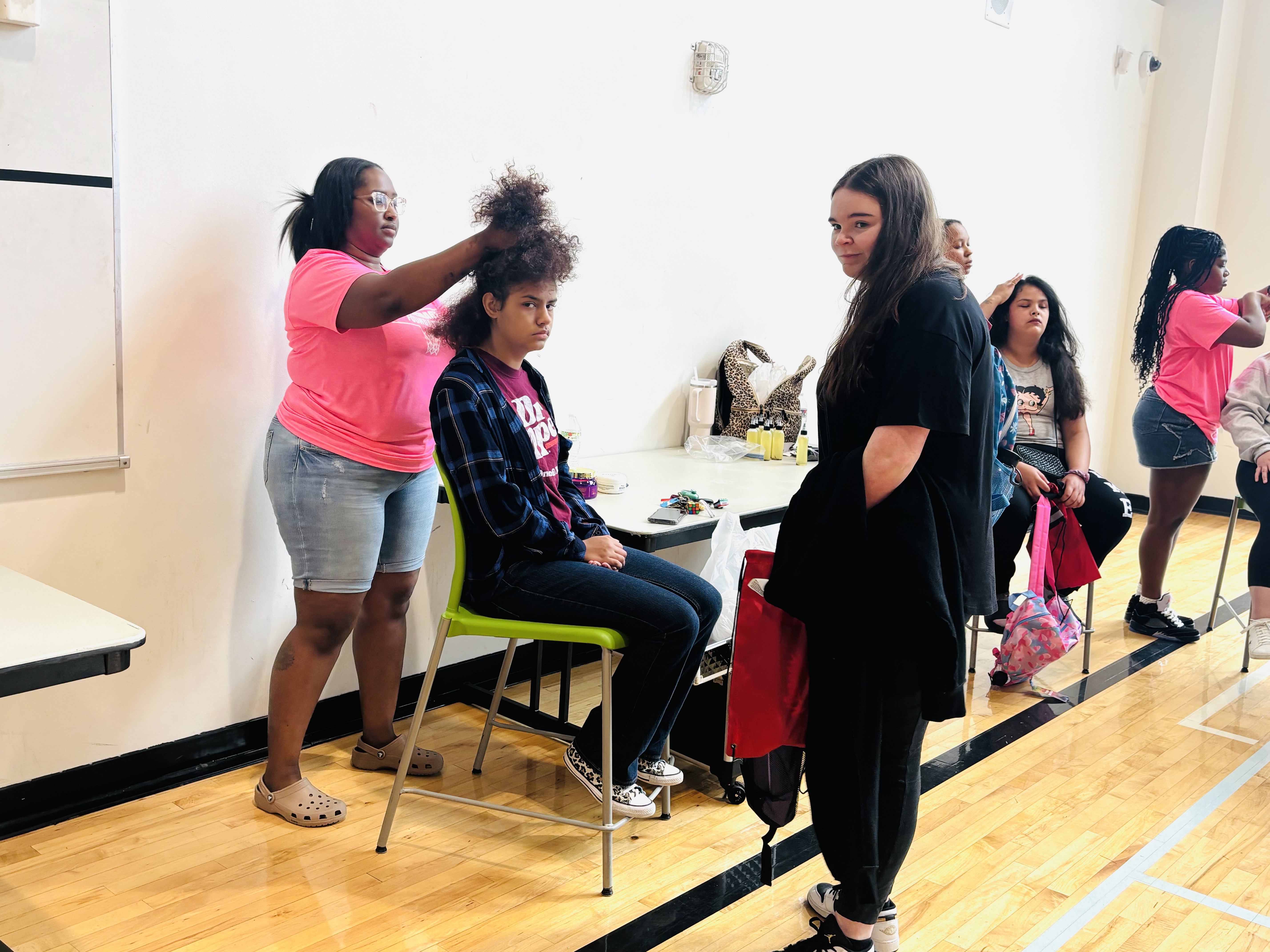 A stylist works on a student's hair at the free hair station during the 2025 Back to School Bash.