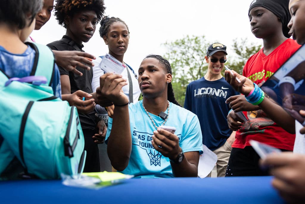 Silas Demary Jr. signing autographs surrounded by kids at the bash