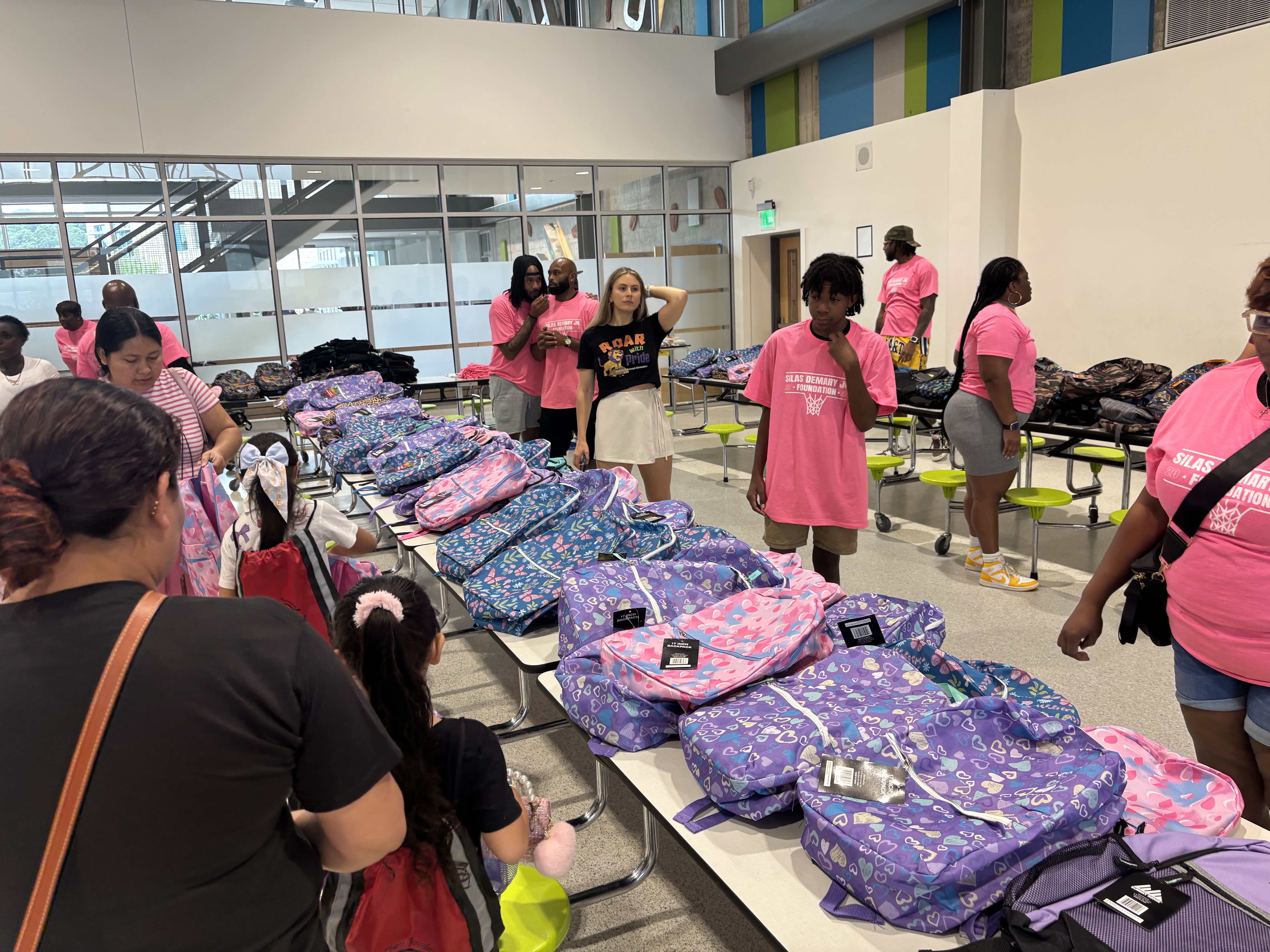 Rows of backpacks laid out on tables as volunteers greet families at the 2025 Back to School Bash.