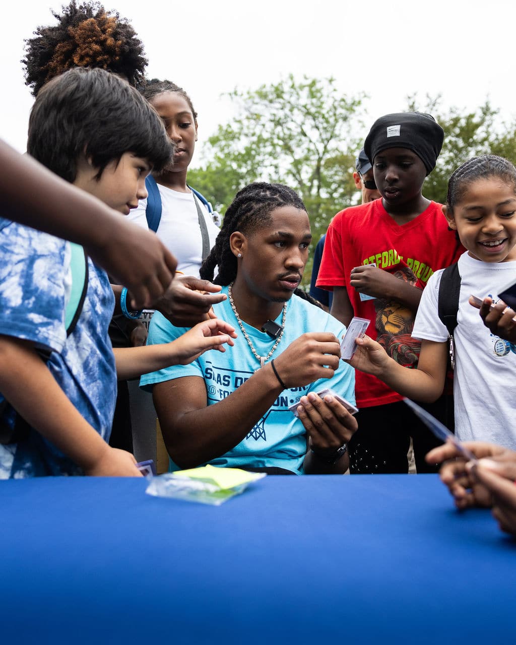 Silas Demary Jr. handing signed photos to kids on the green