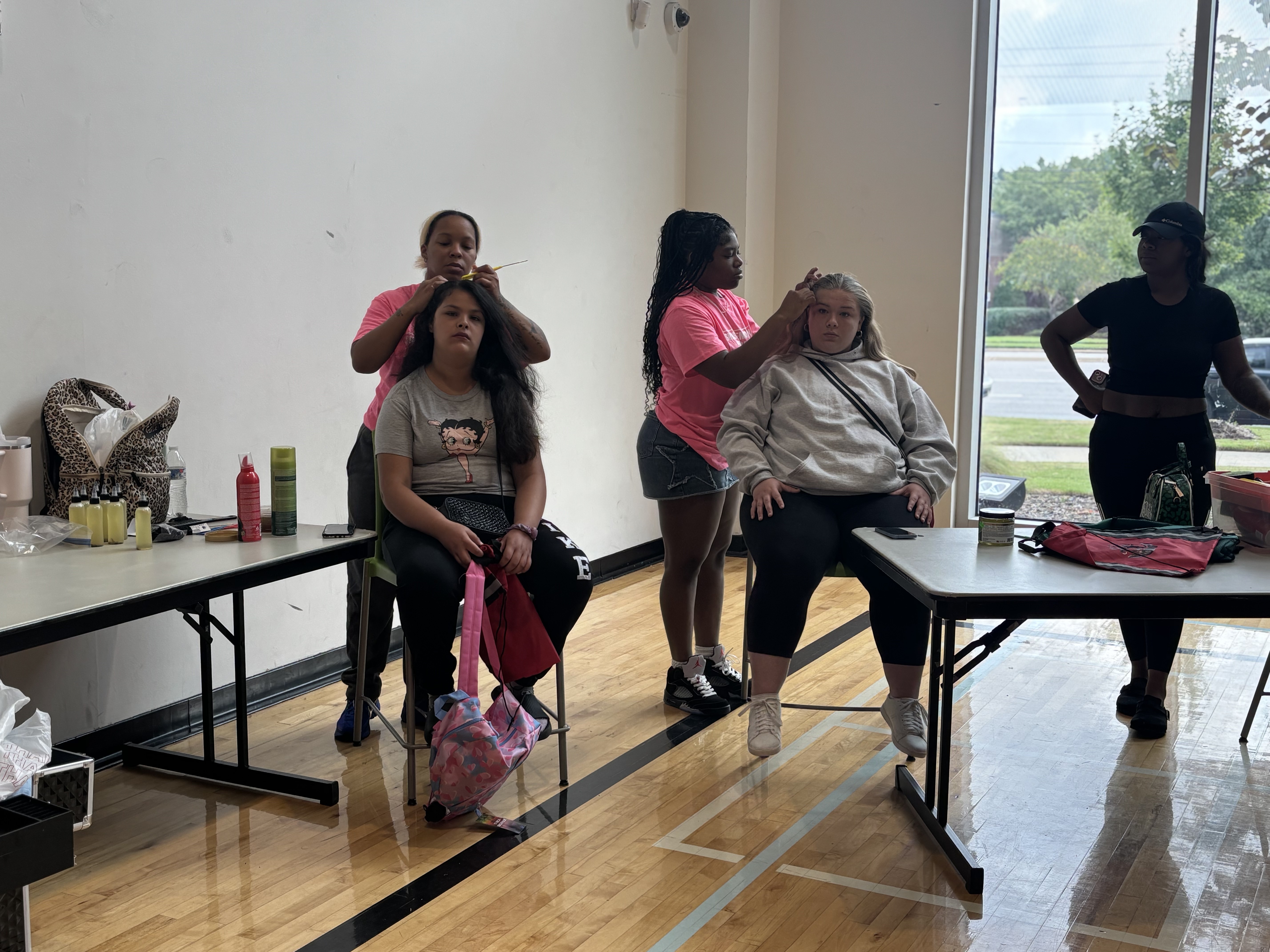 Two stylists braid and style students' hair before the school year at the 2025 Back to School Bash.