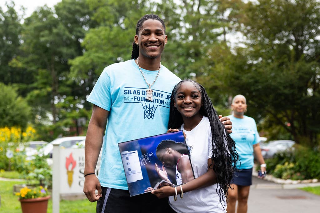 Silas Demary Jr. with a young fan holding an autographed photo