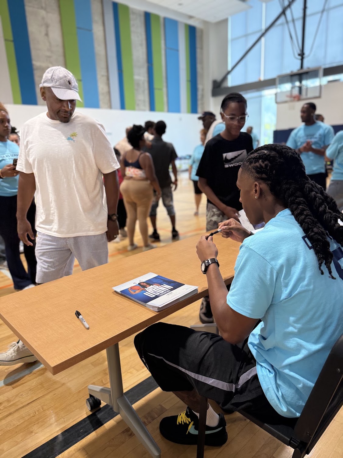 Silas Demary Jr. signs an autograph for an adult attendee at the 2026 Raleigh Back to School Bash.
