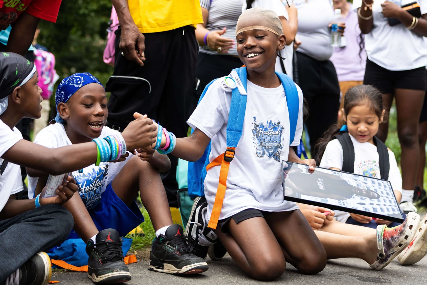 Smiling kids with backpacks at a foundation community event