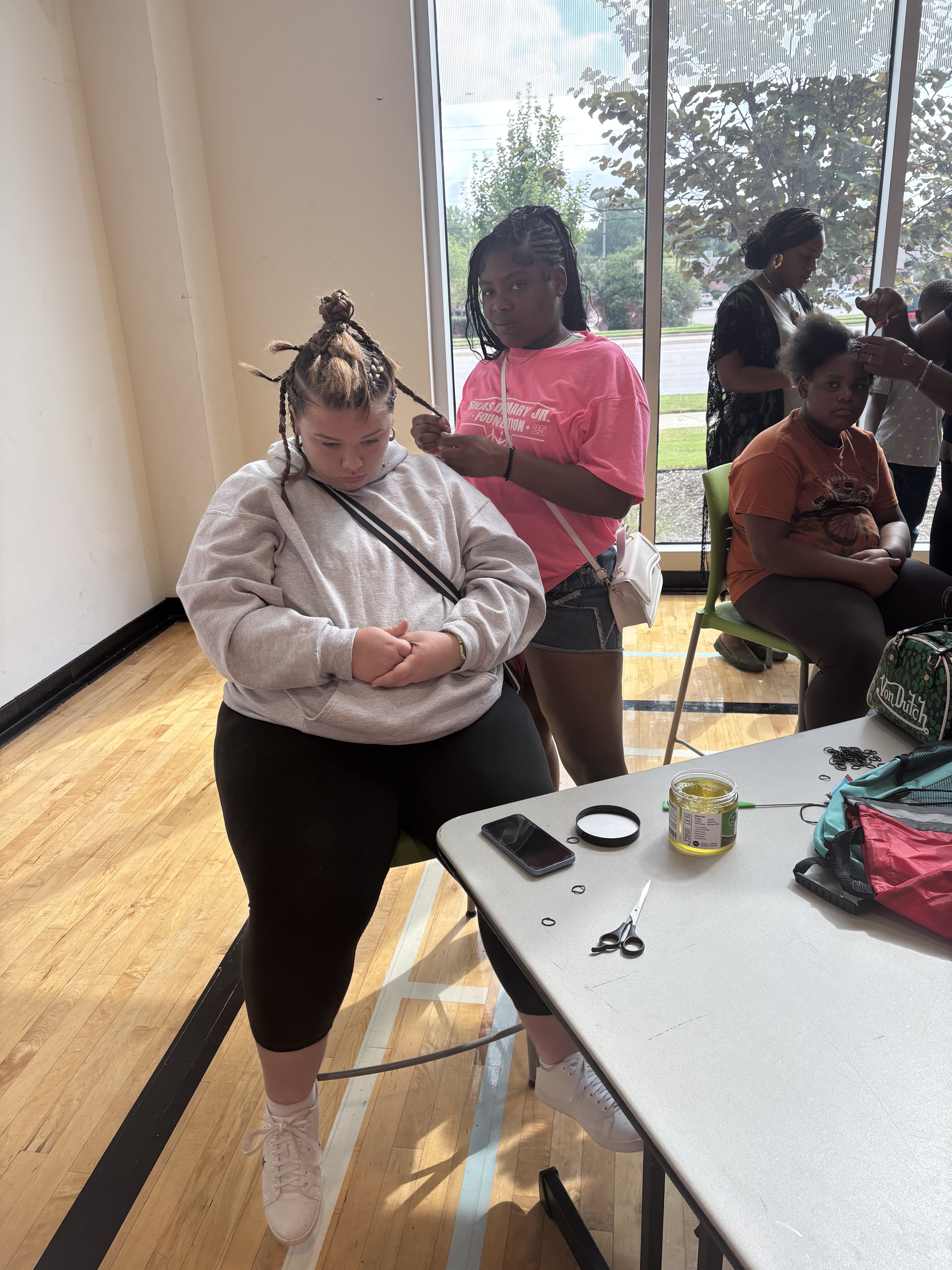 A volunteer braids a student's hair at the free hair station at the 2025 Back to School Bash.