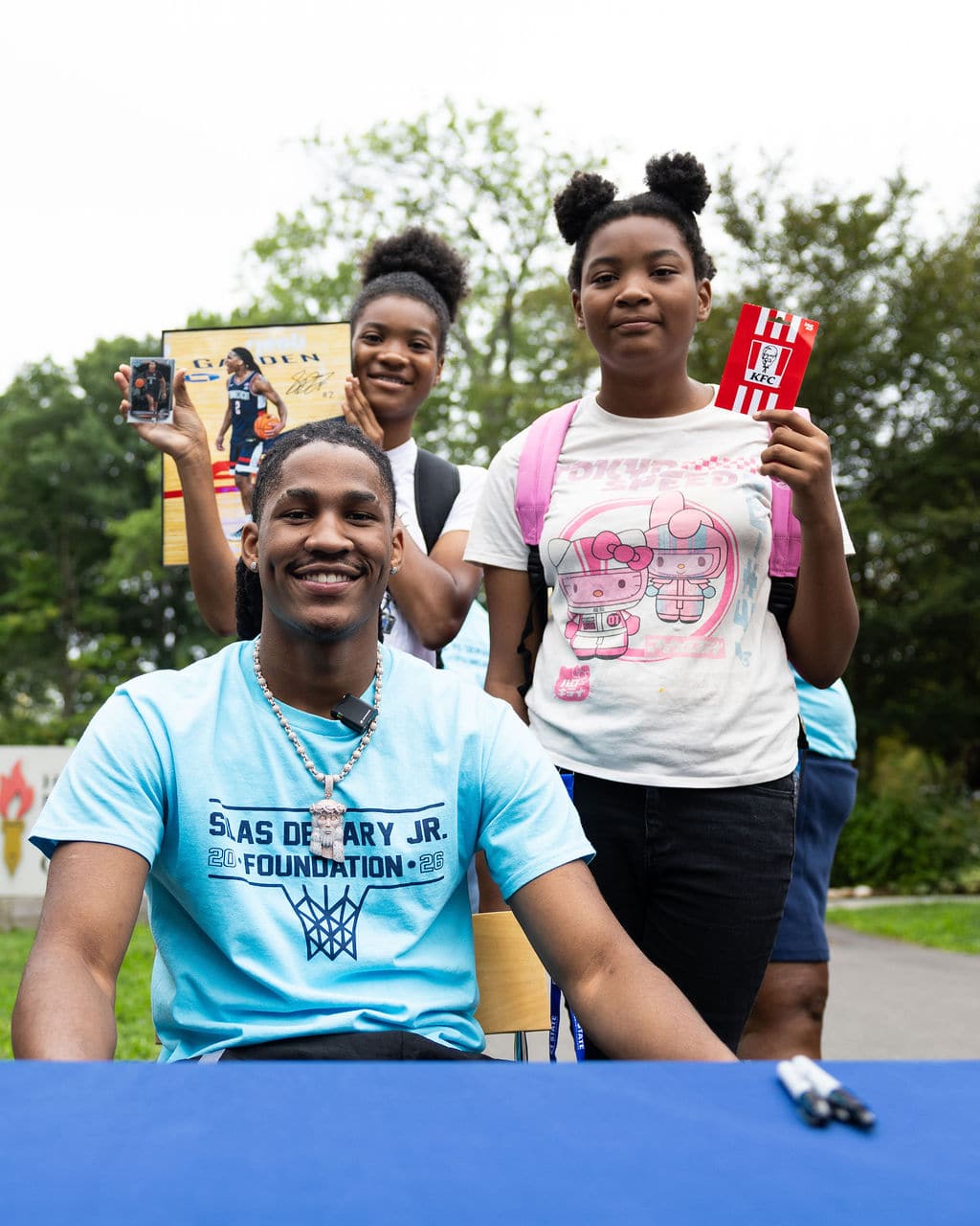Silas Demary Jr. with young fans showing off signed photos and a prize card