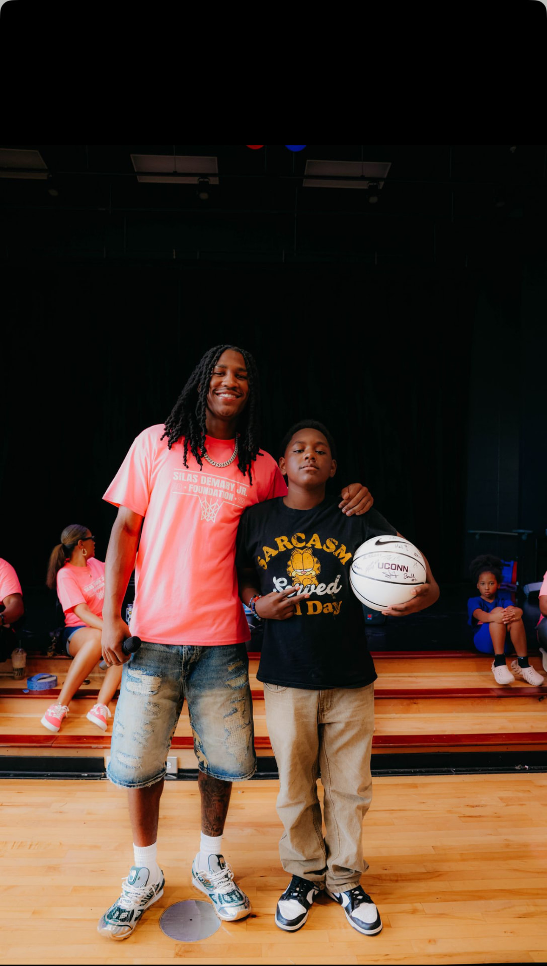 Silas Demary Jr. puts his arm around a young fan holding a signed UConn basketball at the 2025 Back to School Bash.