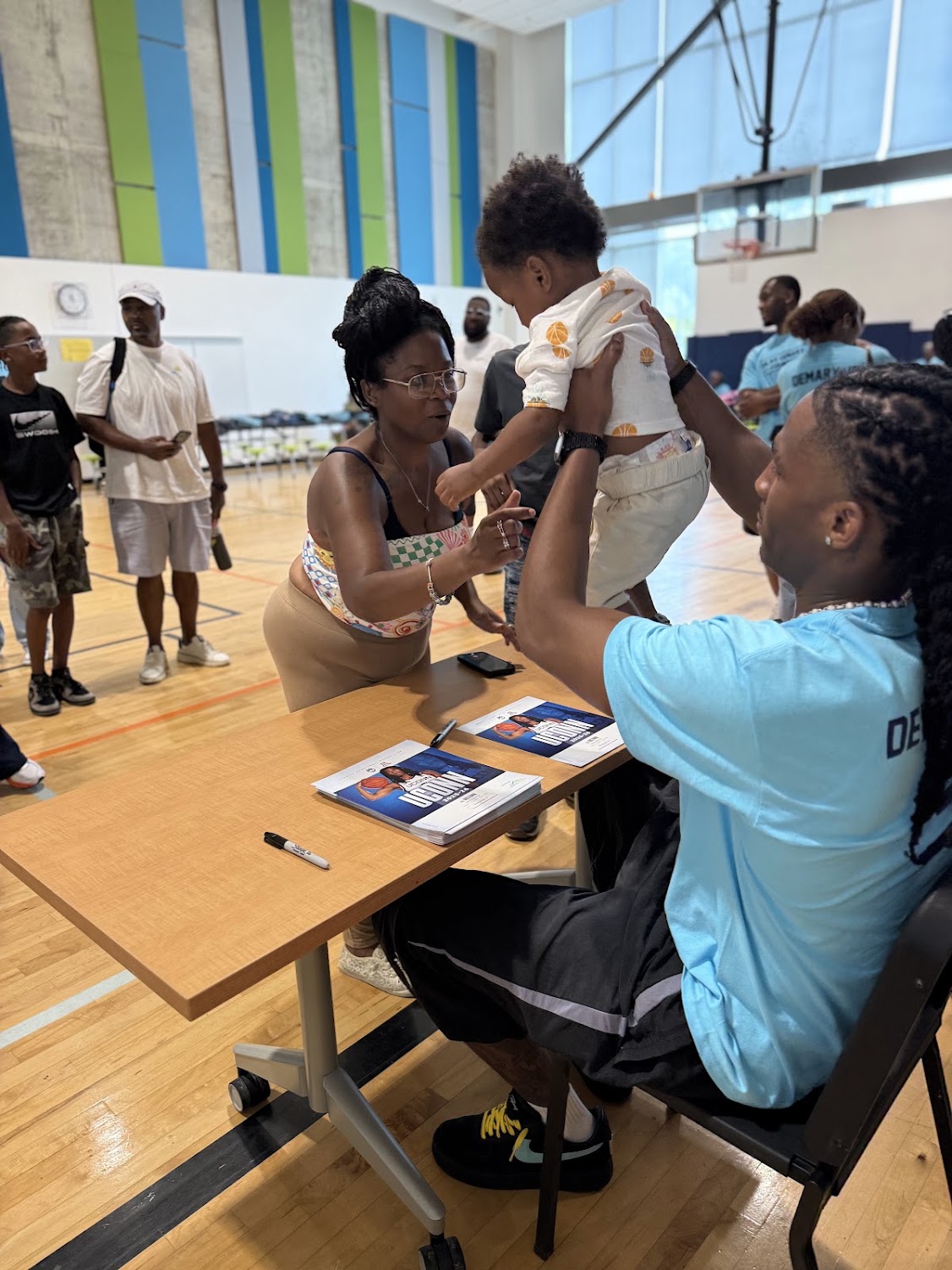Silas Demary Jr. hands a toddler to a family member during the 2026 Raleigh Back to School Bash.