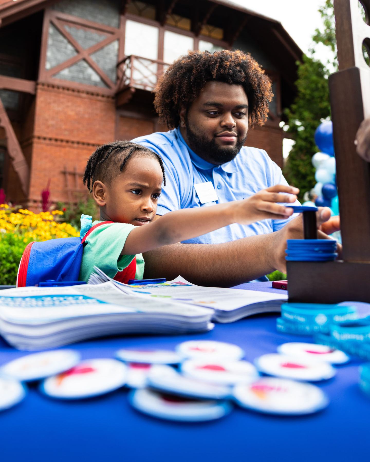 A volunteer helping a child with school supplies at the activity table