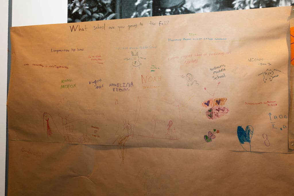 Guests share the schools they are heading to on a paper wall