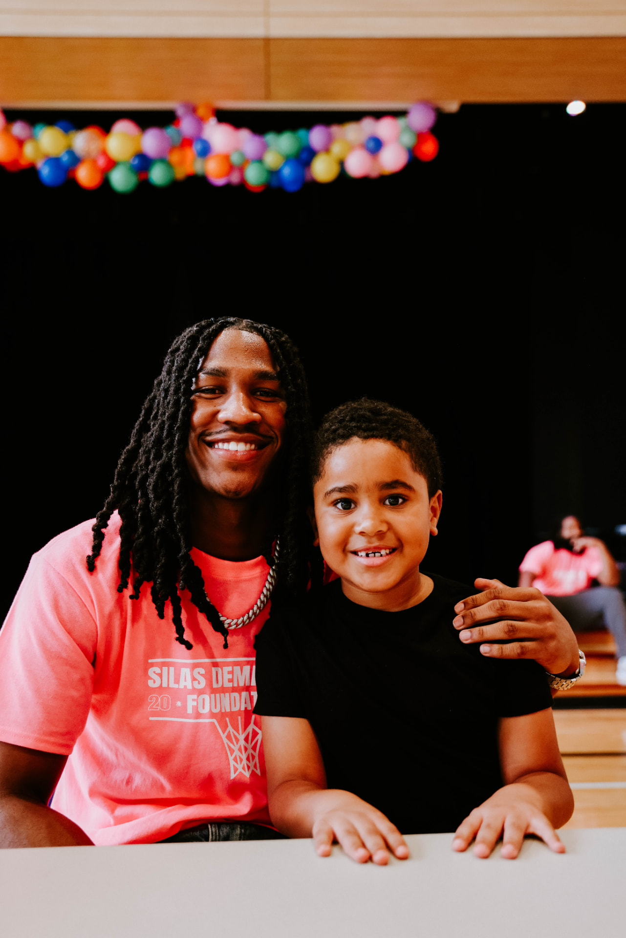 Silas Demary Jr. puts his arm around a young boy at the giveaway table at the 2025 Raleigh Back to School Bash.